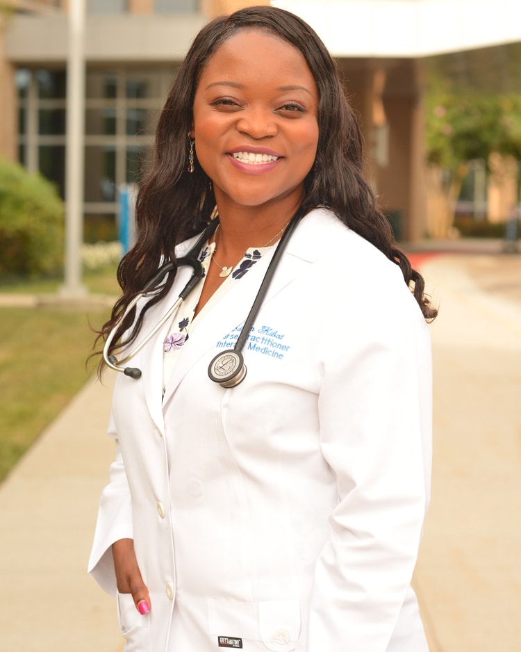 Smiling healthcare professional in a white coat, wearing a stethoscope, stands outdoors, embodying a welcoming and confident demeanor.
