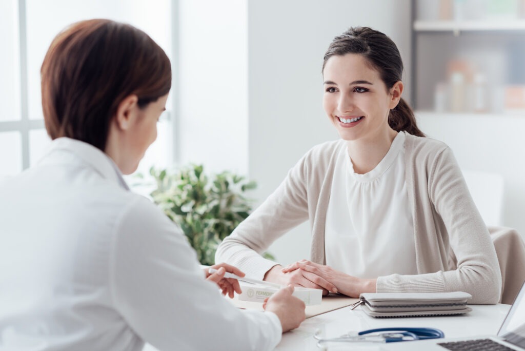 A healthcare professional discusses treatment options with a smiling patient in a bright, modern clinic setting.